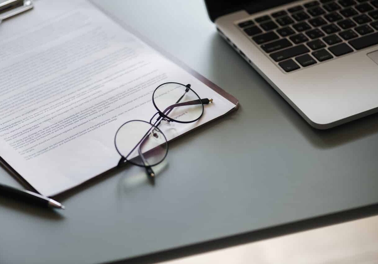 desk with glasses paperwork and computer